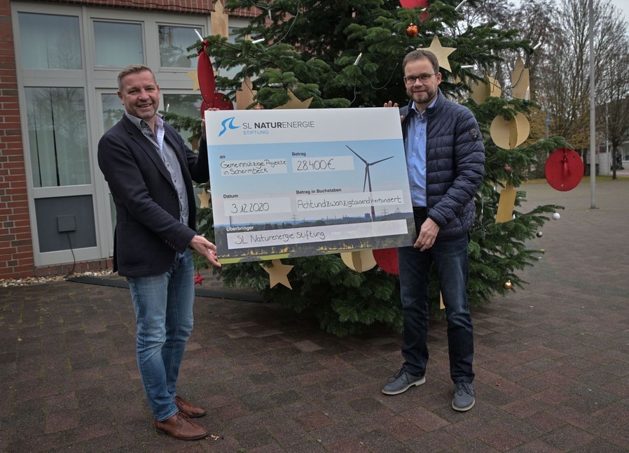 Bürgermeister Mike Rexforth und Joachim Schulenburg (SL NaturEnergie) bei der Scheckübergabe vor dem Schermbecker Rathaus.