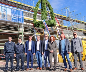 Vertreter der Feuerwehr, Politik und Stadtverwaltung stehen unter dem Richtkranz an der Feuerwache in Kirchhellen.