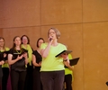 Die Chormitglieder singen auf einer Bühne.