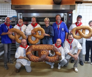 Die Brezelmajestäten gemeinsam mit den Brezelbäckern und dem Riesenbrezel in Markus Kläseners Backstube.
