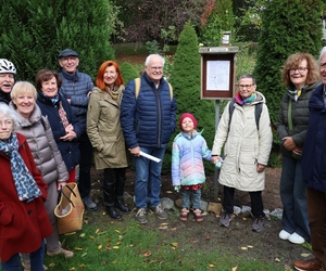 Die Initiatoren des Lyrikpfads und einige Lyrikfreunde stehen im Bauerngarten vor der Gedichtstaffel am Hof Jünger.
